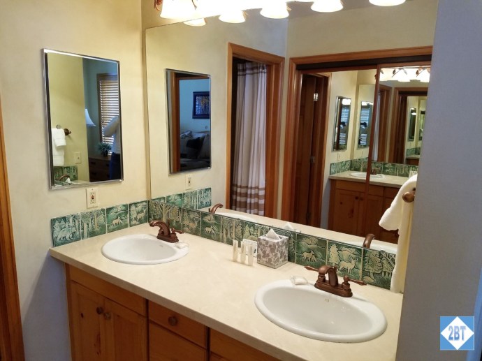 Double sinks in the second bath with the closet reflected in the mirror